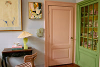Room interior with a pink door, green cabinet, and decorative items.