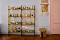 Shelving unit with decorative items in a room with a pink door and artwork on the wall.