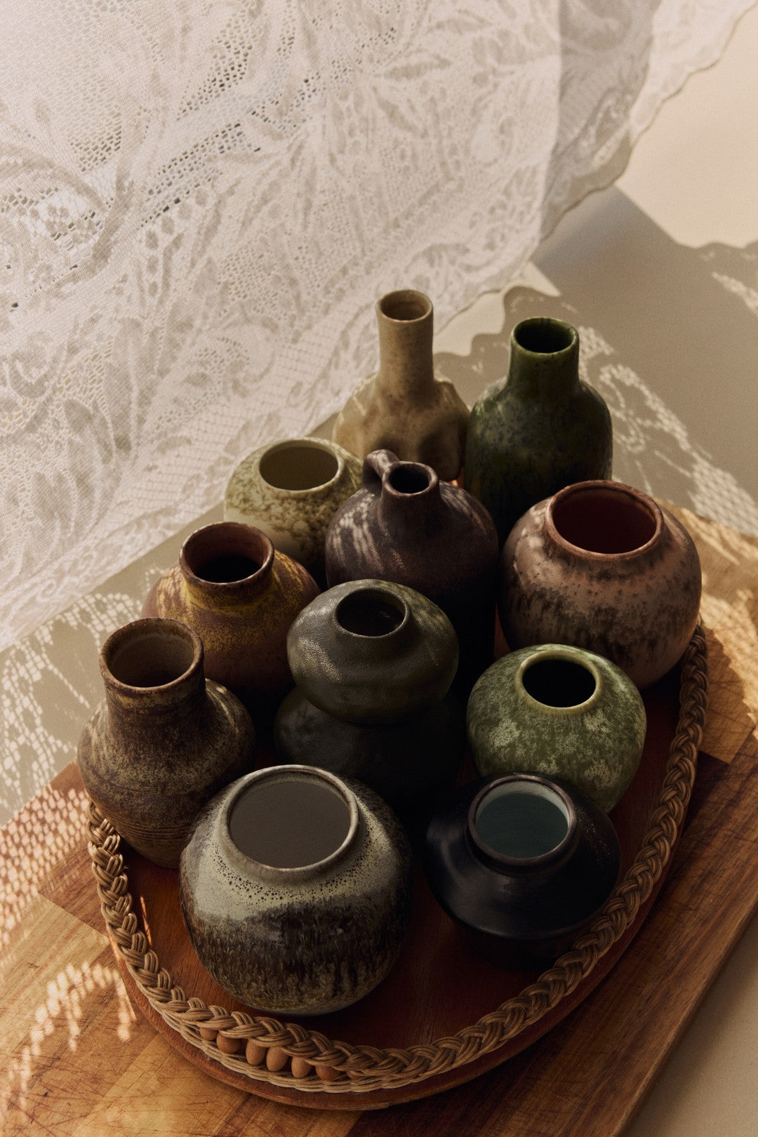 Collection of ceramic vases on a woven tray with a textured white background