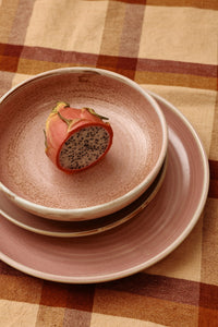 Stack of ceramic plates with a dragon fruit on a checkered tablecloth