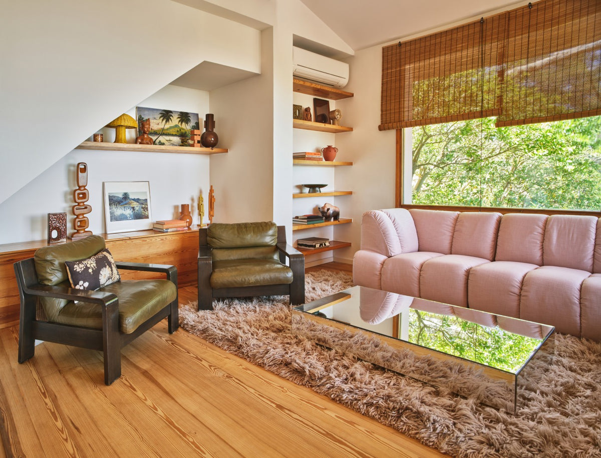 Living room with pink sofa, green chairs, and a mirror coffee table.