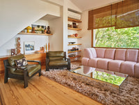 Living room with pink sofa, green chairs, and a mirror coffee table.