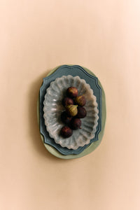 Decorative wall art with a scalloped edge and small figurines on a beige background