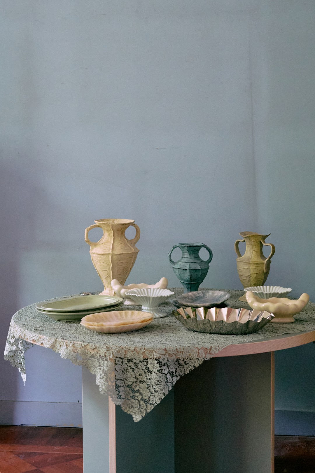 Table with ceramic vases and bowls against a plain wall
