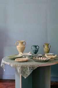 Table with ceramic vases and bowls against a plain wall