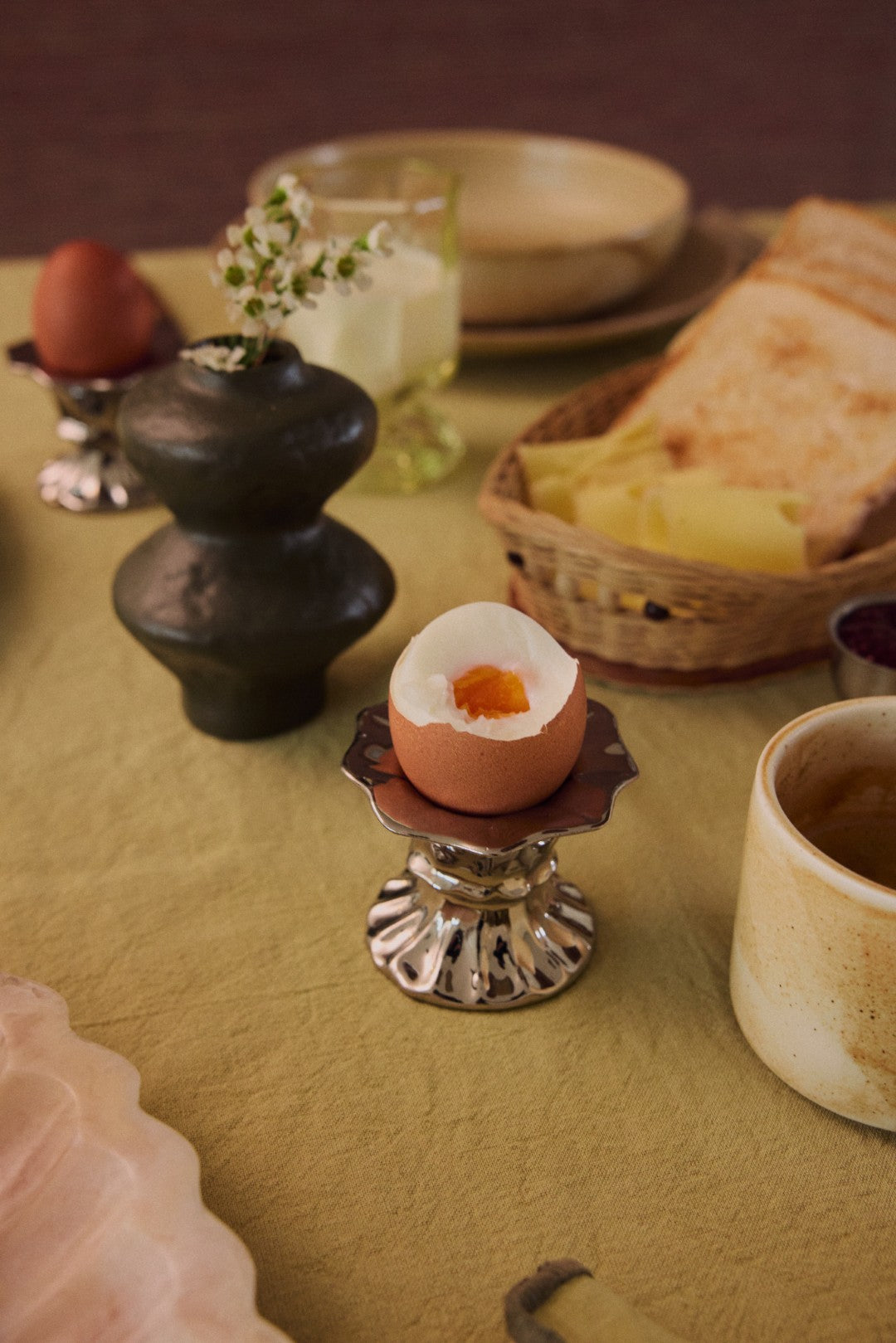 Egg on a decorative stand with a blurred background of food items