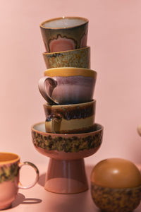 Stack of ceramic cups with decorative patterns on a pink background