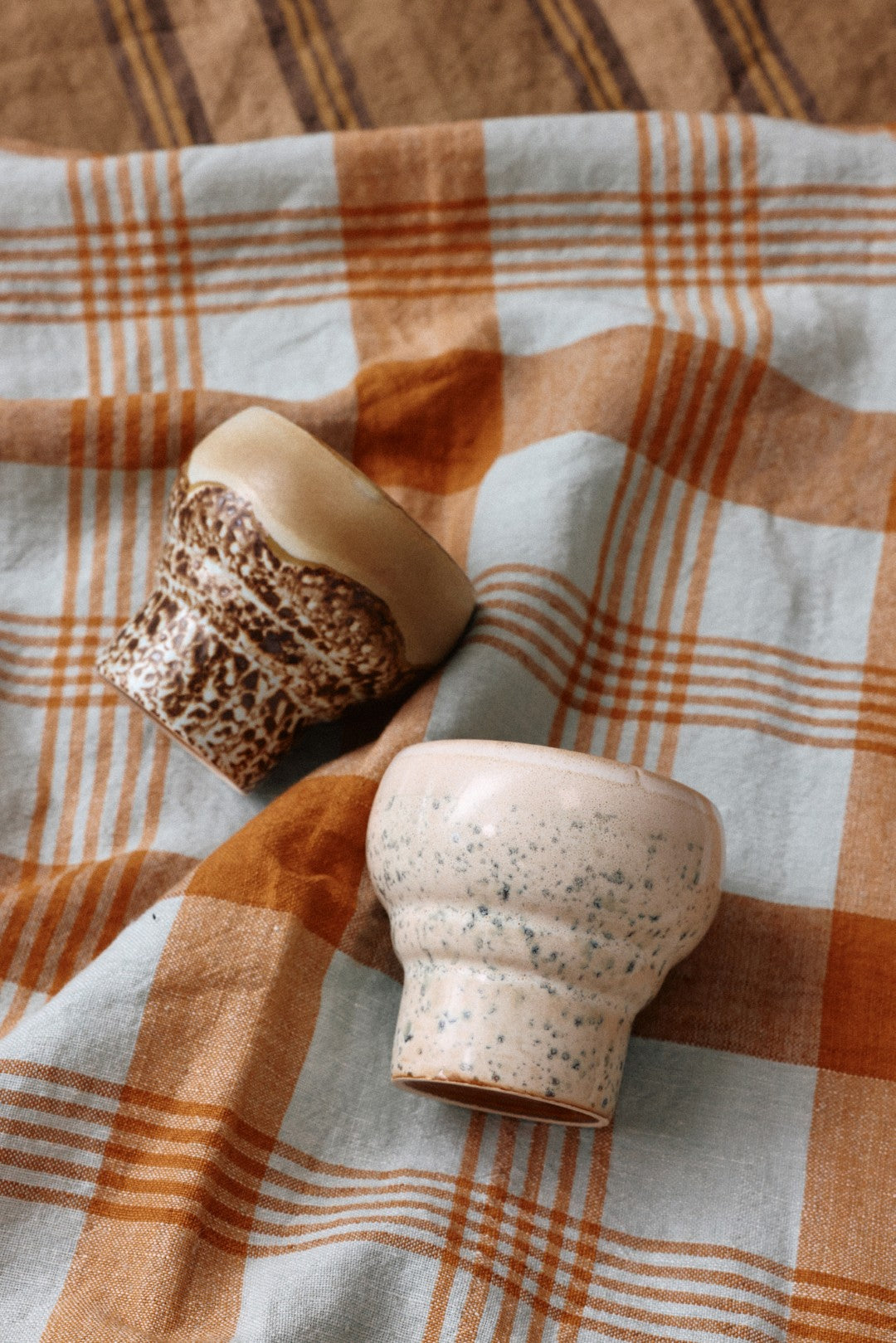 two stoneware mugs an a table cloth