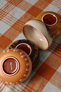 Three ceramic containers with lids on a checkered tablecloth