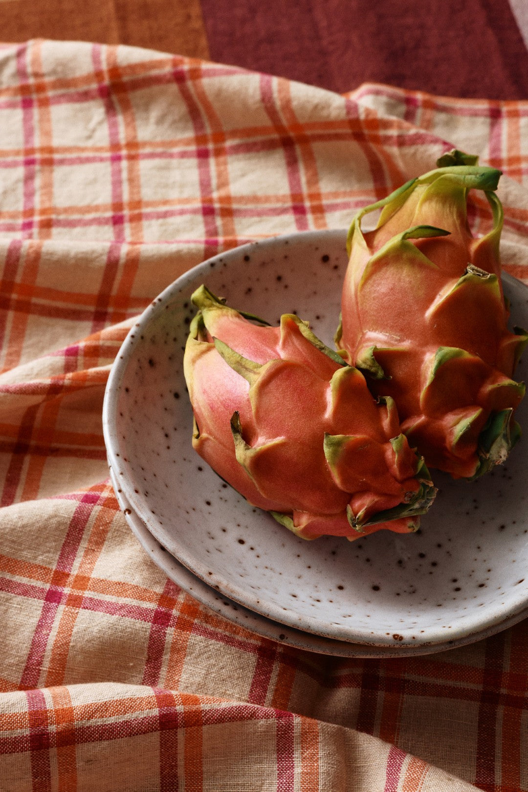 Dragon fruit on a speckled ceramic plate with a checkered cloth background