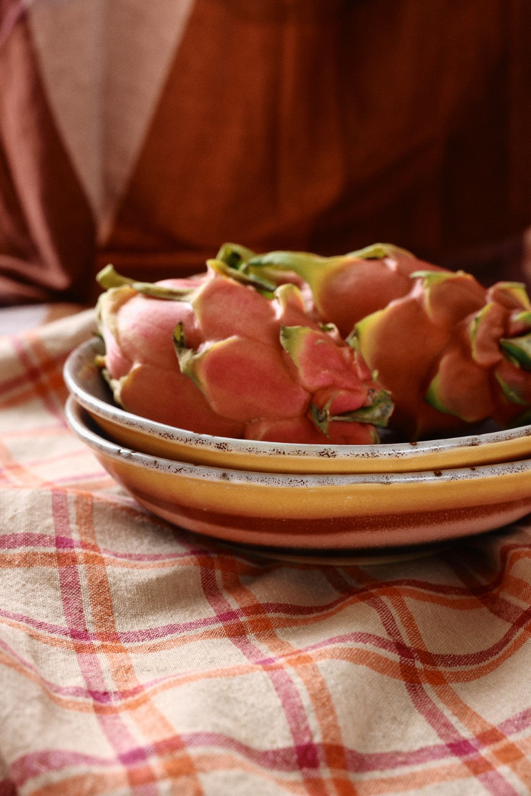 Dragon fruit on a stack of ceramic plates with a checkered tablecloth in the background