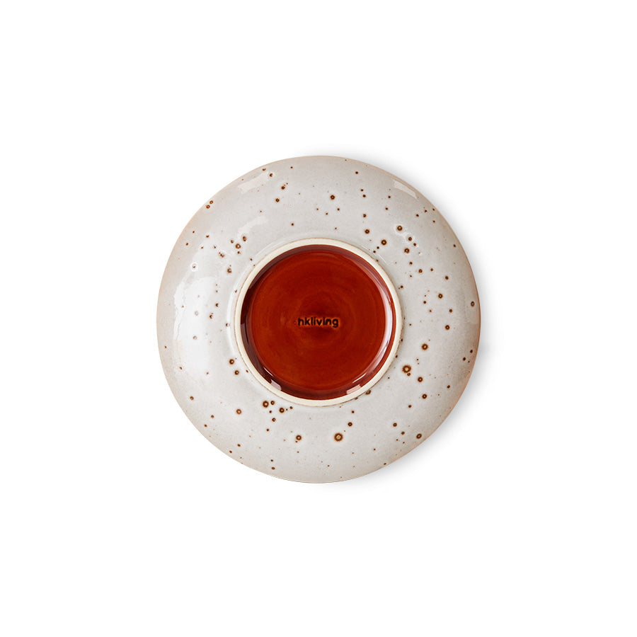 Speckled ceramic plate with a red interior on a white background