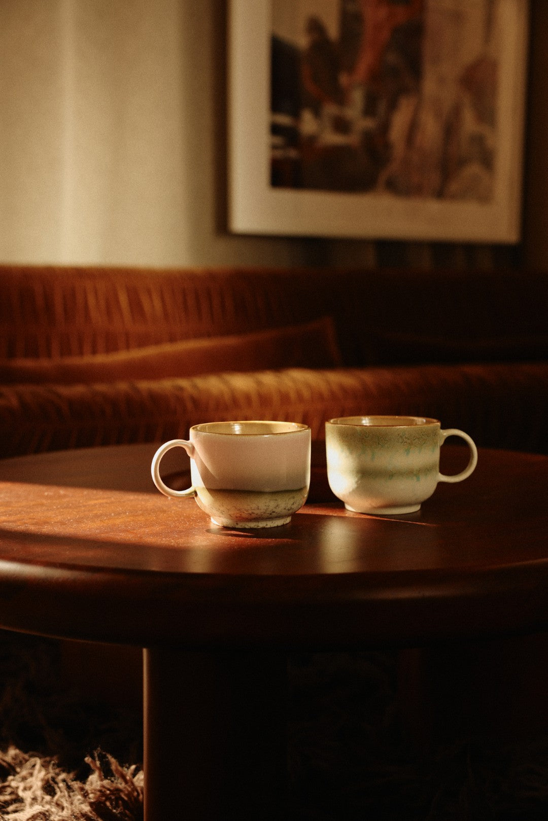 Two ceramic cups on a wooden table with a warm, dimly lit background.