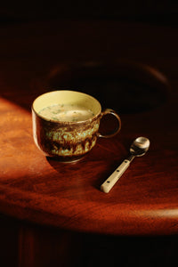 Ceramic mug with a spoon on a wooden surface