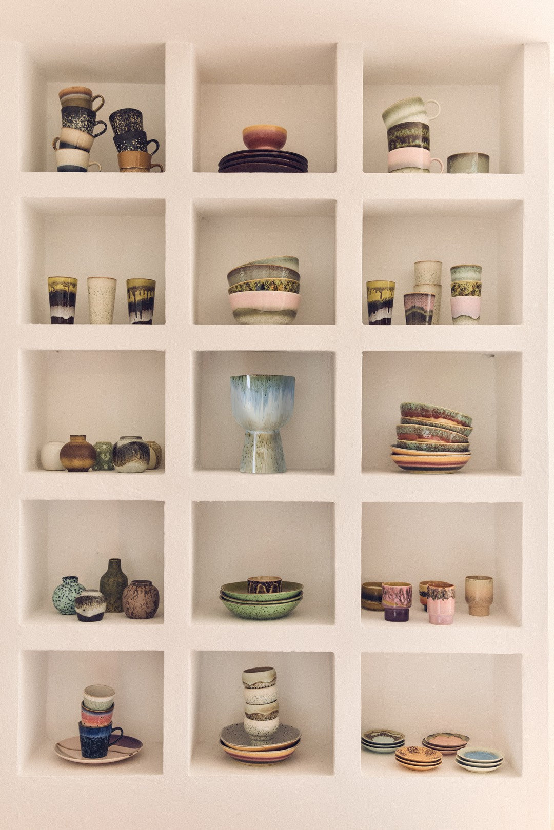 Shelving unit with various ceramic items including cups, bowls, and vases.