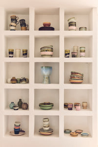 Shelving unit with various ceramic items including cups, bowls, and vases.