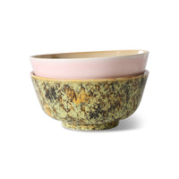 Two ceramic bowls, one with a pink interior and yellow exterior, the other with a greenish-brown exterior, on a white background.