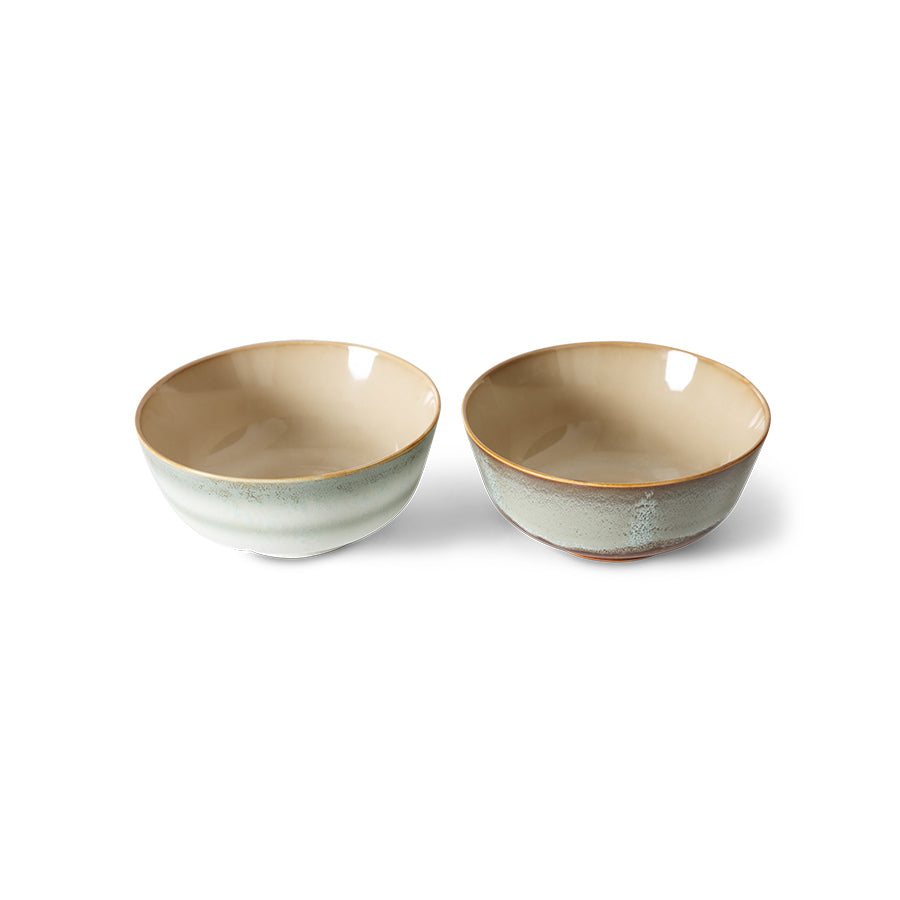 Two ceramic bowls with a beige interior and green exterior on a white background