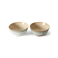 Two ceramic bowls with a beige interior and green exterior on a white background