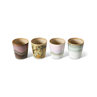 Four ceramic cups with different earthy color patterns on a white background