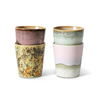 Set of four ceramic cups with earthy tones on a white background