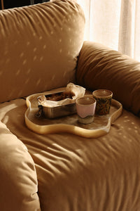 Tray with food and drinks on a beige couch