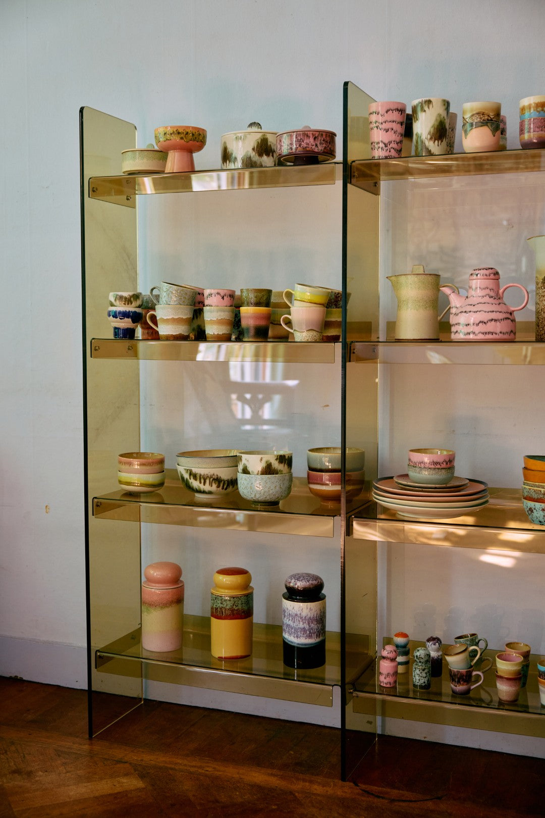 Shelving unit with ceramic pots and vases on a wooden floor.