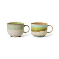 Two ceramic mugs with green and beige glaze on a white background