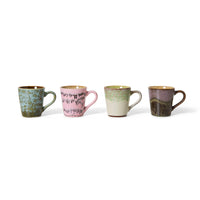 Four ceramic mugs with different earthy tones on a white background