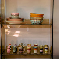 Collection of colorful ceramic items on a glass shelf