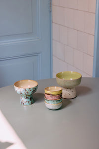 Set of ceramic bowls on a gray surface with a light blue wall and tiled wall in the background.