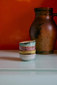Stack of ceramic bowls with a brown vase against an orange wall.