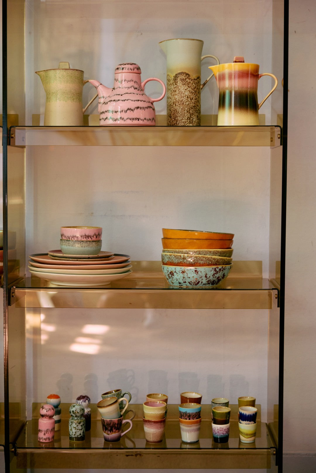 Collection of colorful ceramic items on a glass shelf