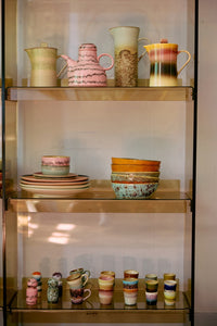 Collection of colorful ceramic items on a glass shelf