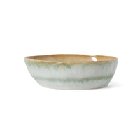 Ceramic bowl with a green and beige glaze on a white background
