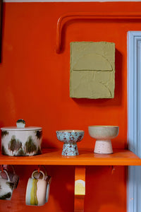 Decorative shelf with ceramic items against an orange wall