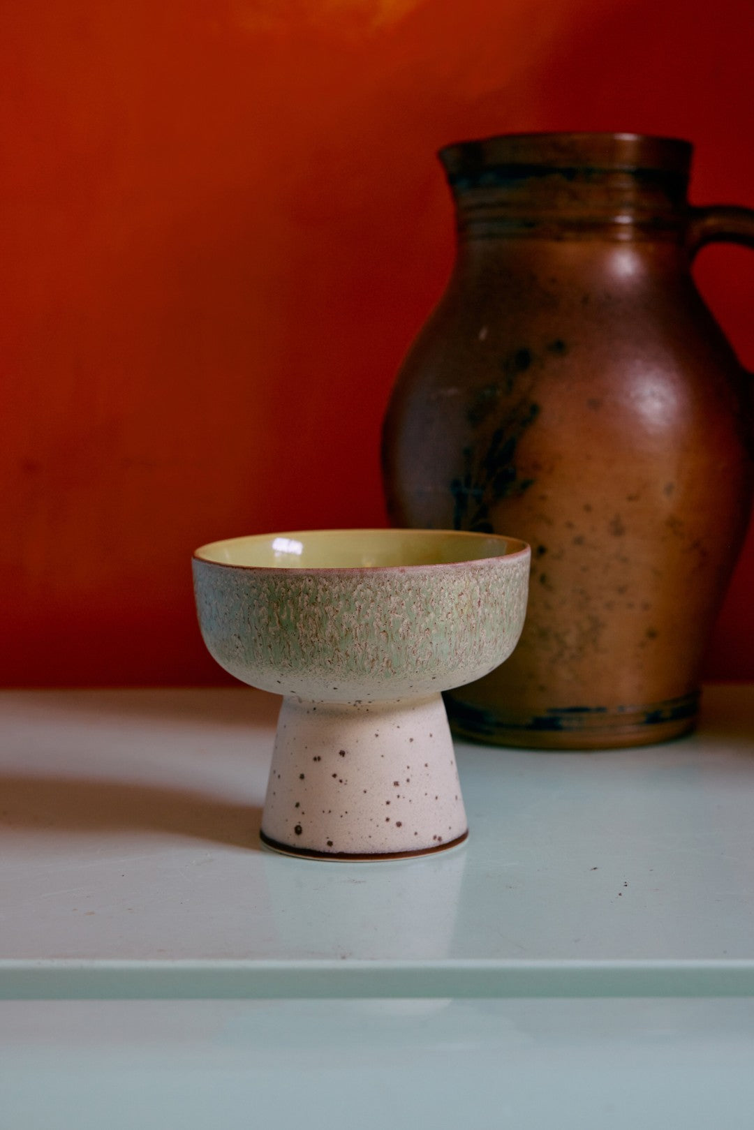 Ceramic bowl with a textured surface on a light surface against an orange wall.