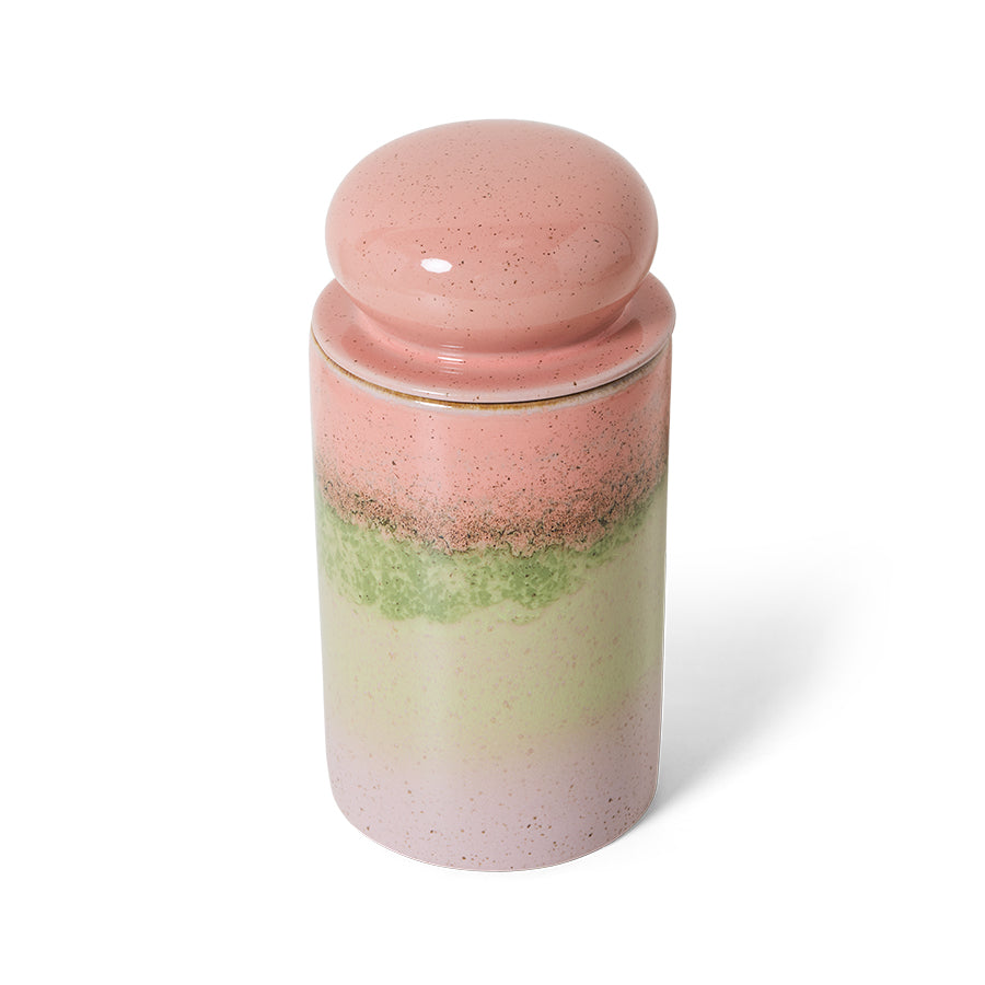 Glass jar with pink and green layers and a pink lid on a white background