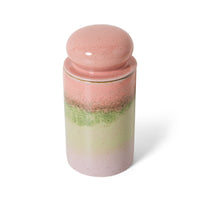 Glass jar with pink and green layers and a pink lid on a white background