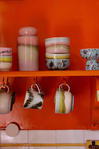Decorative shelves with ceramic items against an orange wall.