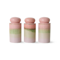Three gradient ceramic jars with pink and green layers on a white background