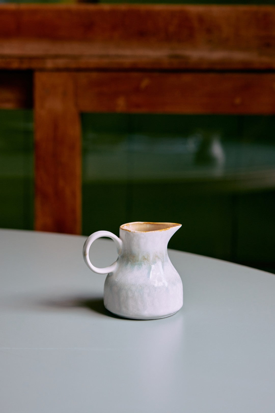 White ceramic pitcher on a light surface with a blurred background
