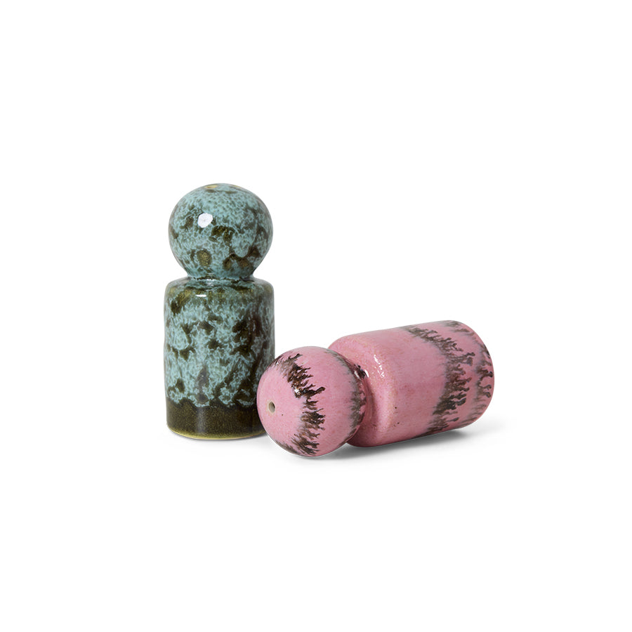 Two ceramic shakers, one green and one pink, on a white background