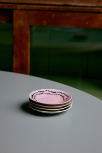 Stack of pink ceramic plates on a gray surface with a blurred wooden table in the background