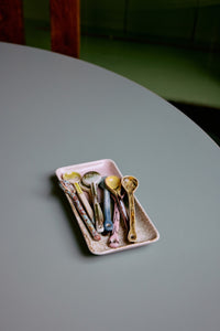 Set of colorful spoons on a small tray on a gray surface