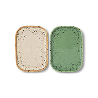 Two ceramic trays, one beige with black speckles and one green with black speckles, on a white background.