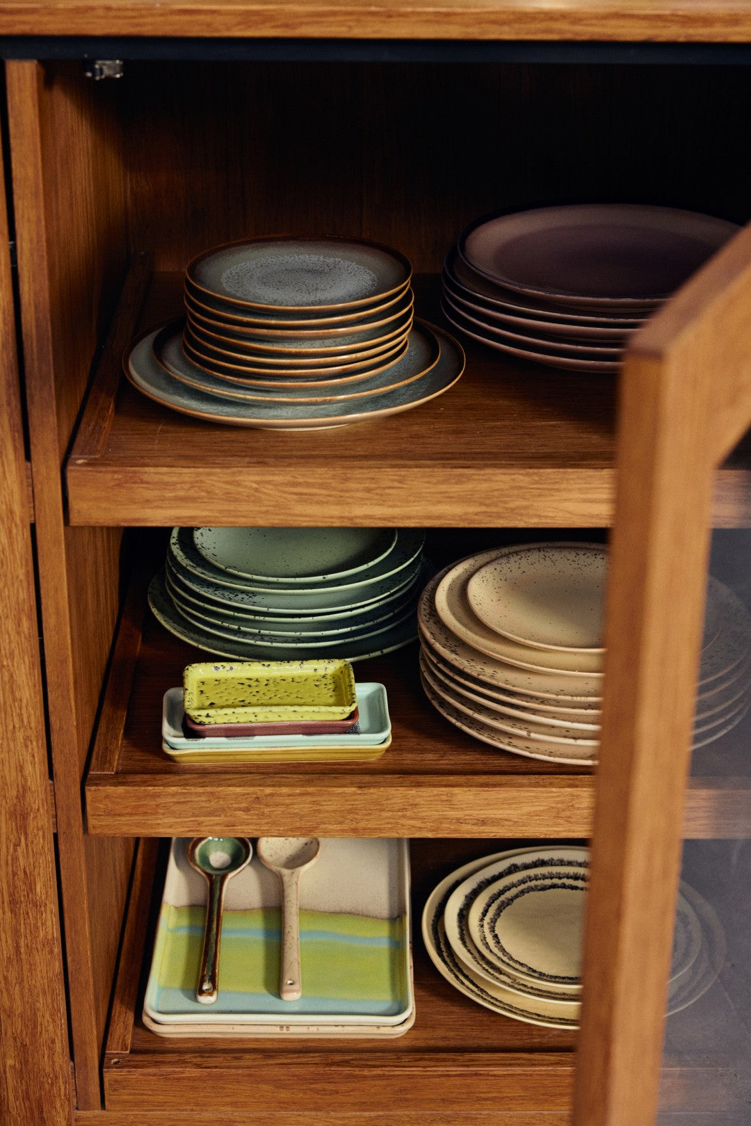Wooden cabinet with stacked ceramic plates and utensils inside