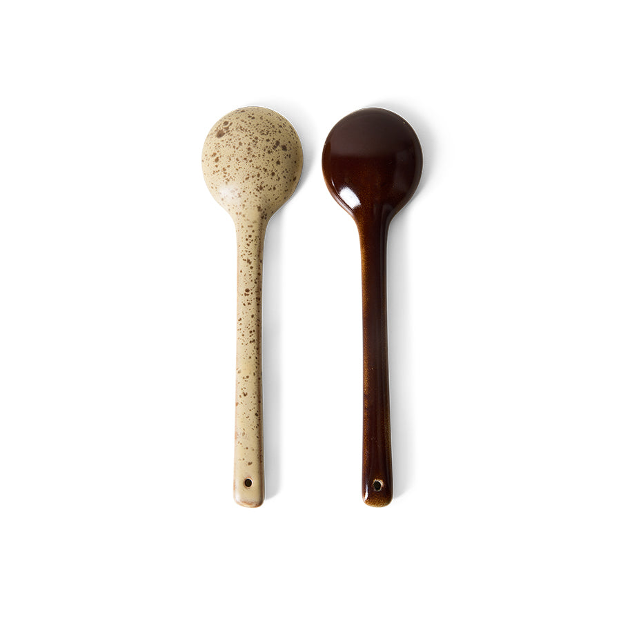 Two wooden spoons, one speckled beige and the other dark brown, on a white background.