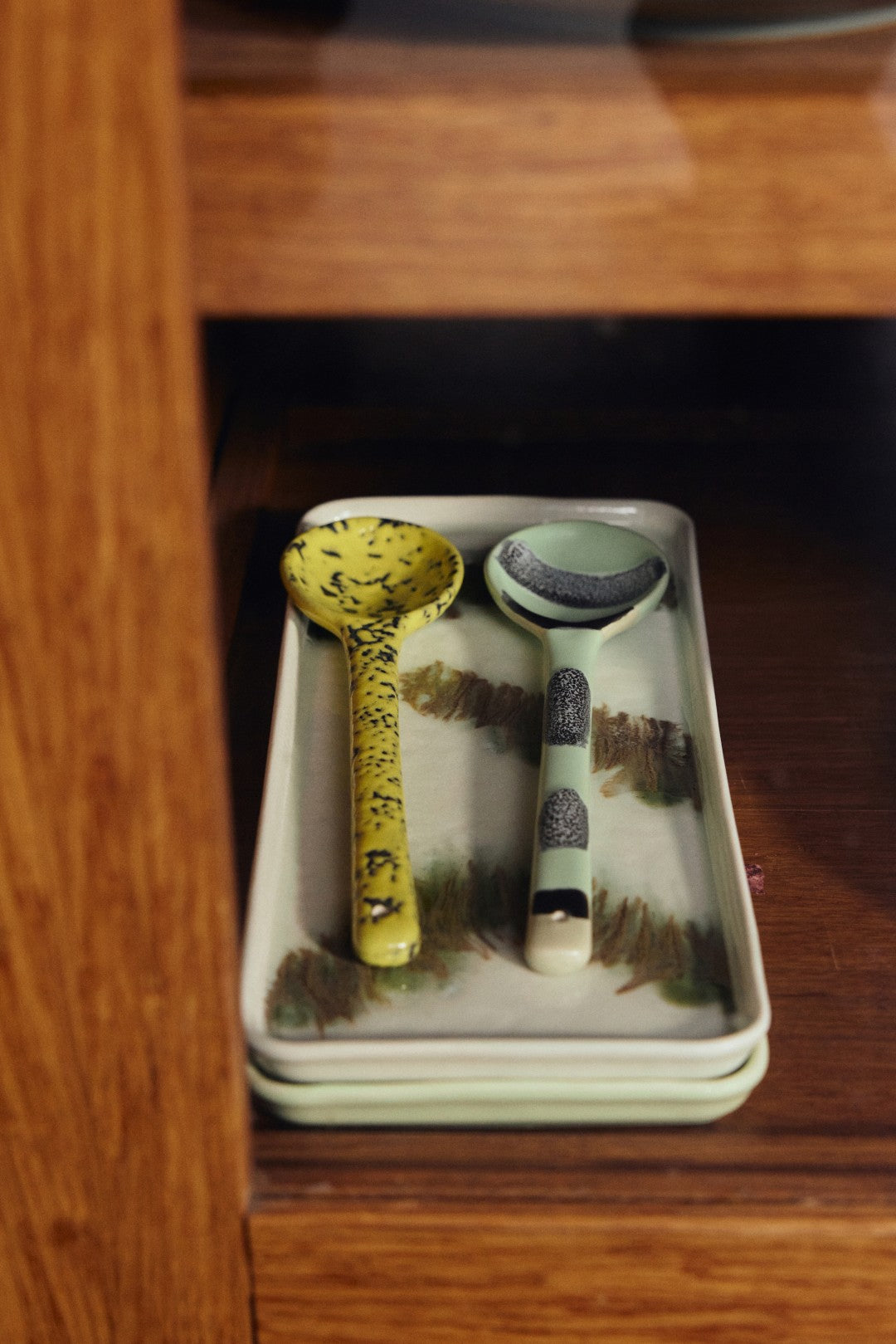 Two ceramic ladles on a rectangular plate with a wooden background