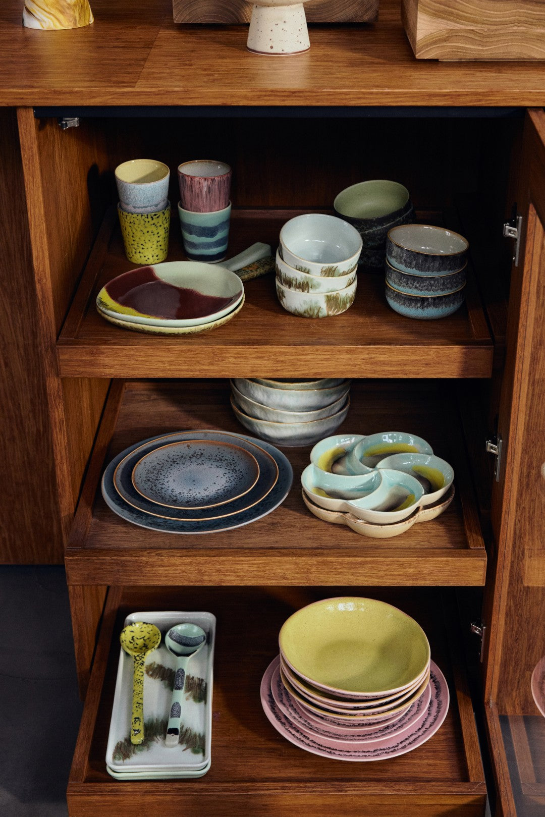 Wooden cabinet with shelves displaying various ceramic dishes and bowls.
